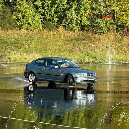 BMW 3er im Drifttraining am Nürburgring Basiskurs auf nasser Driftfläche mit Wasserspritzern