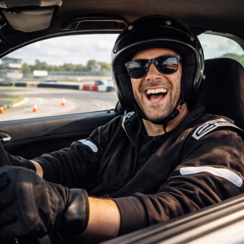 Teilnehmer beim Drifttraining auf der Rennstrecke Meppen Circuit Meppen. Fahrer sitzt lachend im Auto mit Helm während eines Driftkurses und freien Driftens bei Trackday24.