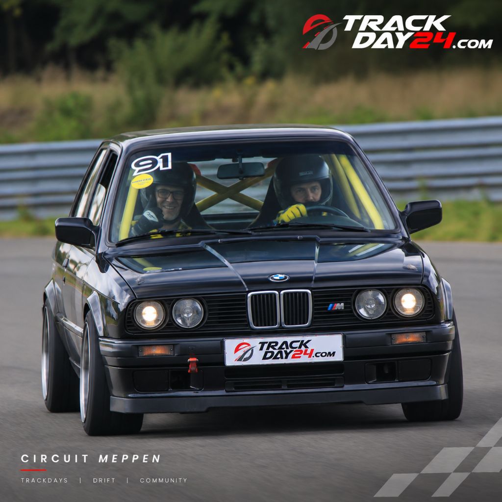 Schwarzer BMW E30 mit Fahrer und Beifahrer beim Trackday von TrackDay24 auf dem Circuit Meppen.