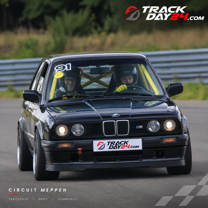 Schwarzer BMW E30 mit Fahrer und Beifahrer beim Trackday von TrackDay24 auf dem Circuit Meppen.